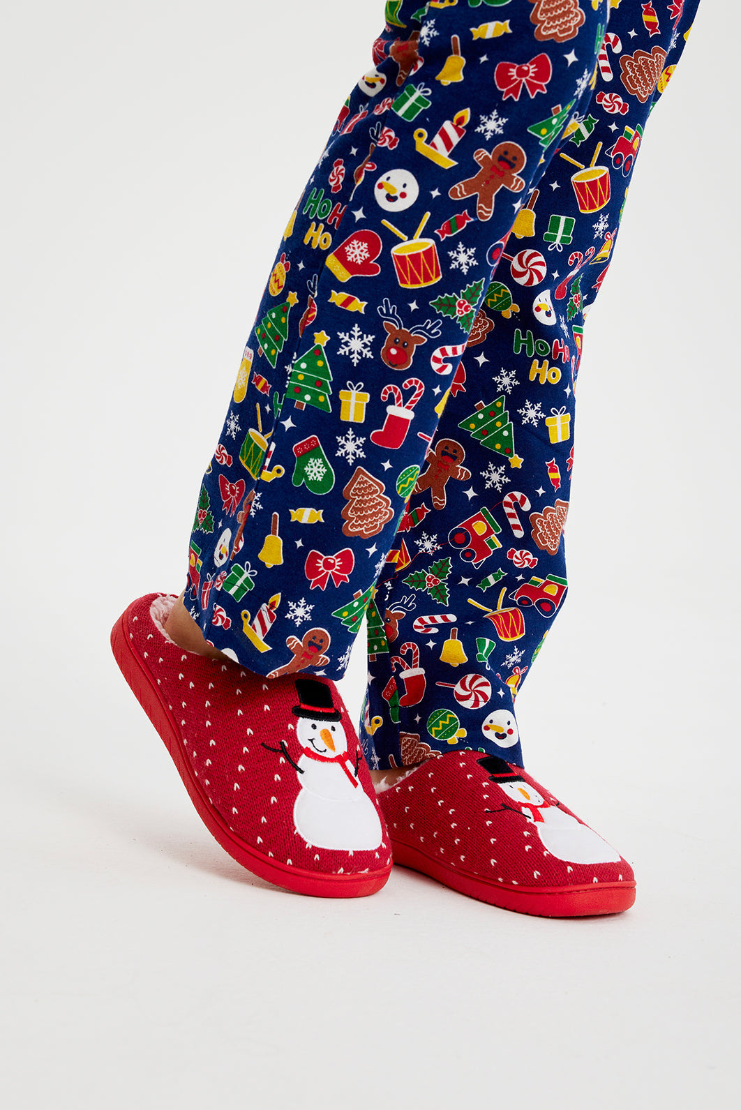 Ein Paar Beine in roten Weihnachtspantoffeln mit einem Schneemann darauf.